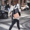 Modernen MoFut Rucksack in Schwarz und Peach, getragen von einer Frau auf der Straße, ideal für Schule, Uni und Freizeit mit vielen Fächern und 15,6" Laptopfach.