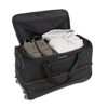 Große schwarze Travelite Trolley Reisetasche mit Rollen, dehnbar und teilweise gefüllt, ideal für Reisen. Sichtbare Sportschuhe und Kleidung im Inneren.