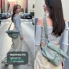 Junge Frau trägt eine nachhaltige Crossbody Tasche LUCA in Hell Grün, umgeben von urbaner Kulisse mit Bäumen und modernen Gebäuden, repräsentiert Funktionalität und Stil.