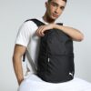 Junger Mann mit sportlichem PUMA teamGOAL Backpack Core in Schwarz auf heller Oberfläche, ideal für Sport und Alltag.