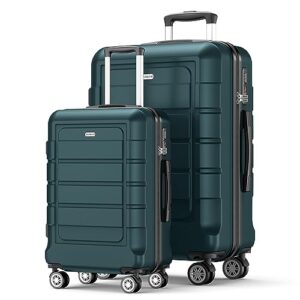 Two dark blue suitcases are sitting next to each other on a white surface. The larger suitcase is slightly behind the smaller one, and they both have black handles. The suitcases appear to be made of a shiny material and are equipped with wheels for easy transportation. A TSA-approved lock can be seen on one of the suitcases.